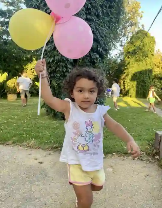 Niña con globos, preparándose para otro juego en su cumpleaños